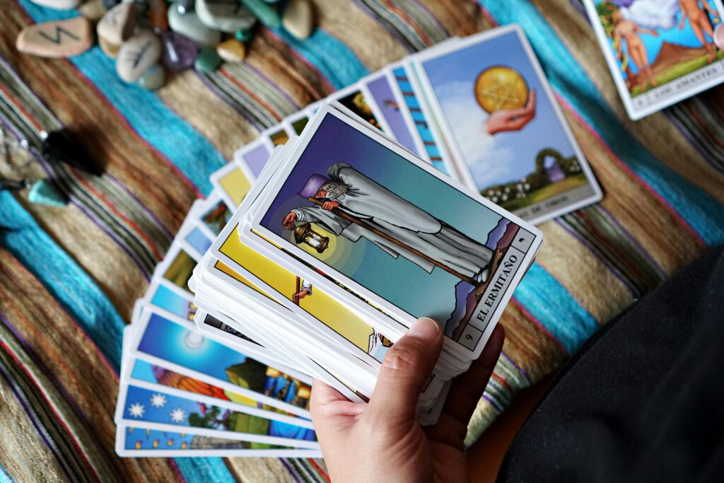A close-up of a person holding tarot cards for a reading on a textured cloth.