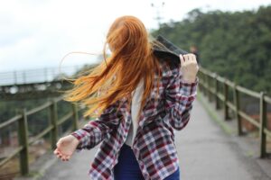 Portrait of a redhead woman outdoors with hair blowing in the wind.